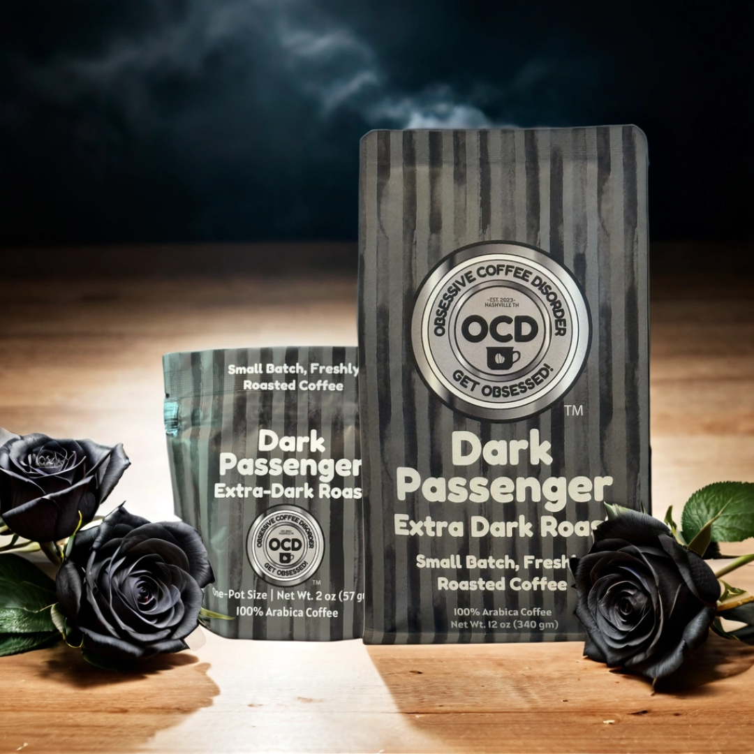 Two packages of OCD Coffee's Dark Passenger Extra Dark Roast coffee on a wooden surface with black roses.