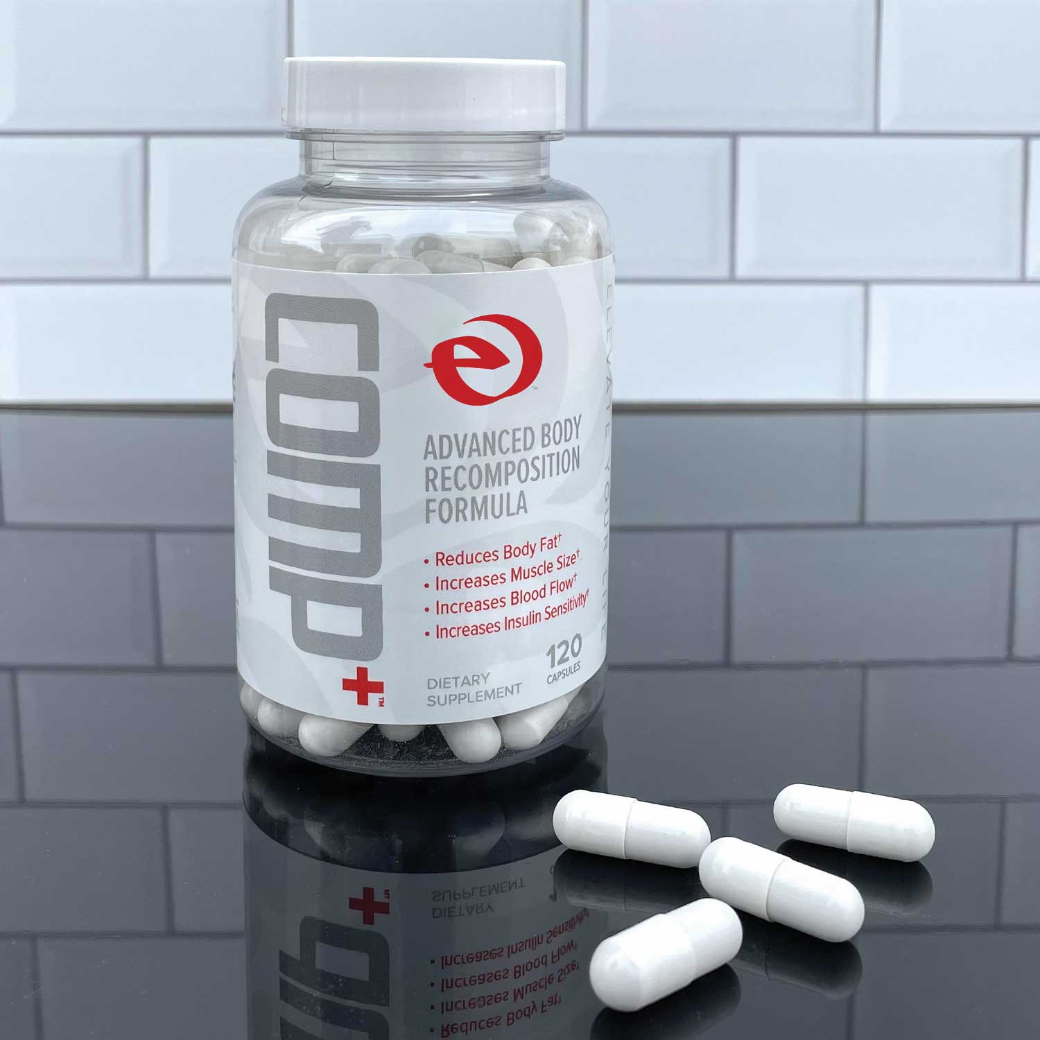 Supplement bottle labeled 'COMP+' with capsules on a reflective surface and tiled background