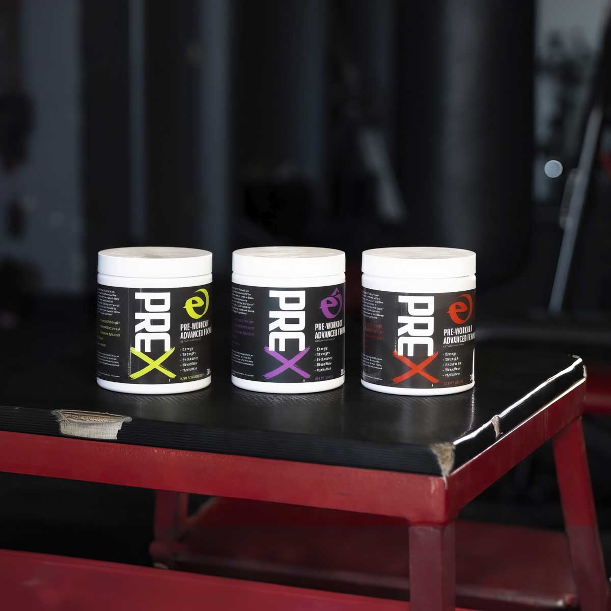 Three containers of PREX supplement on a black surface with a blurred background