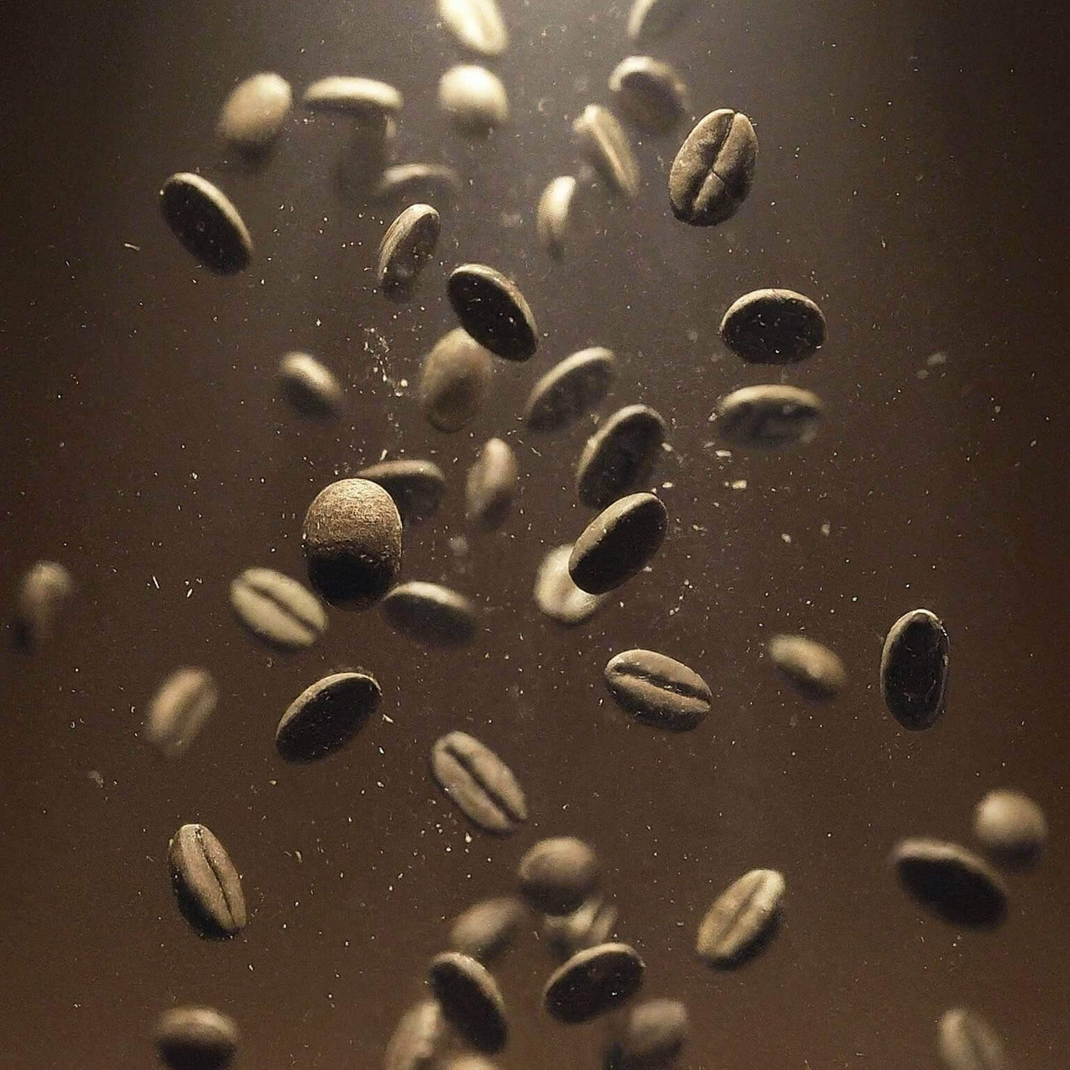 Coffee beans falling against a dark background