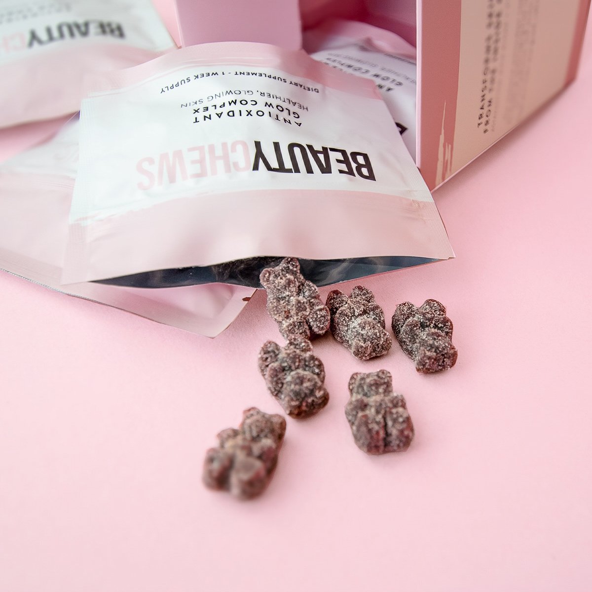 Beauty Chews packaging with some chews spilling out on a pink background