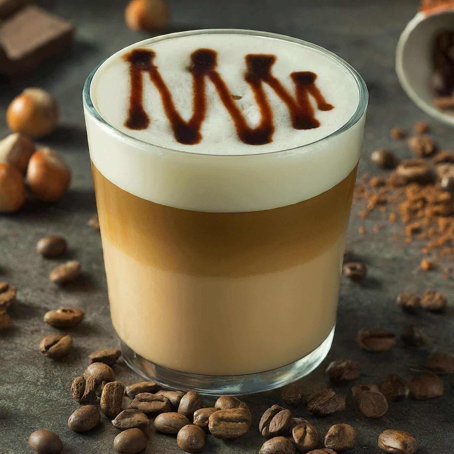 Cappuccino with chocolate syrup design surrounded by coffee beans on a dark surface