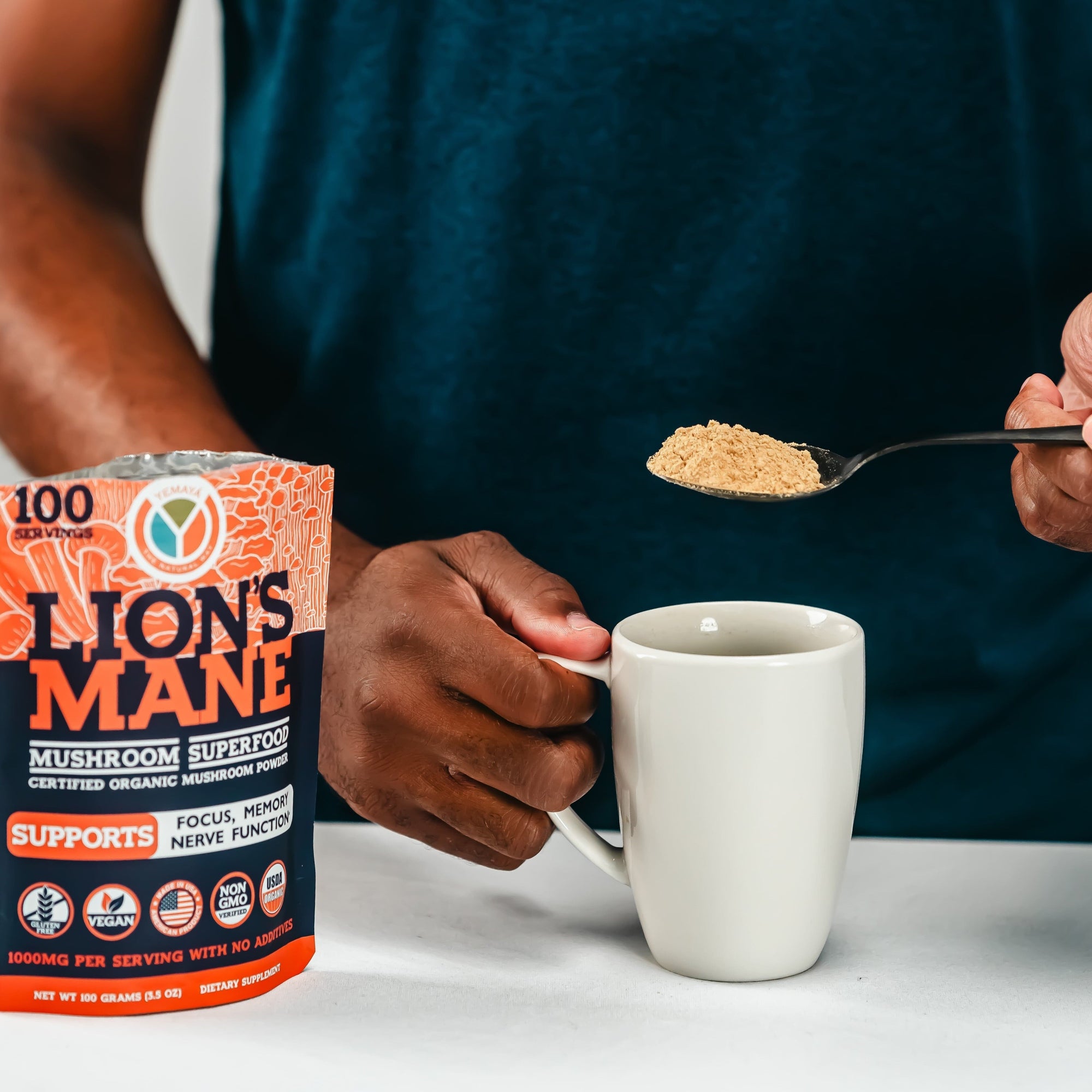 Person adding Lion's Mane mushroom powder to a mug with packaging in the foreground.