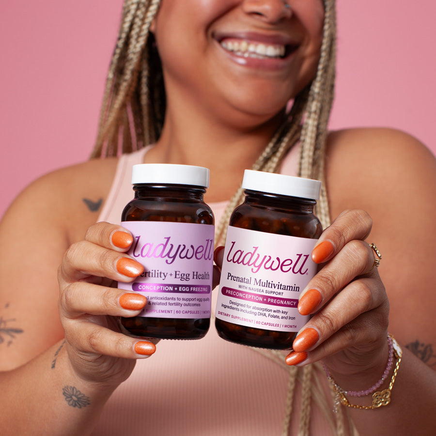 Woman holding two 'ladywell' supplement bottles against a pink background