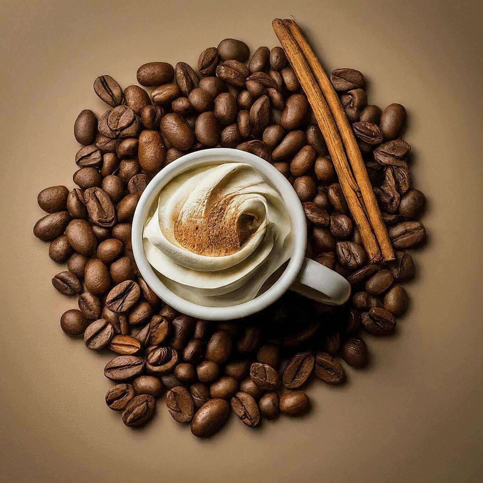 Cup of coffee with cream surrounded by coffee beans and a cinnamon stick on a beige background