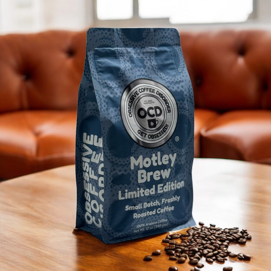 Blue coffee bag labeled 'Motley Brew' by OCD Coffee on a wooden table with coffee beans.