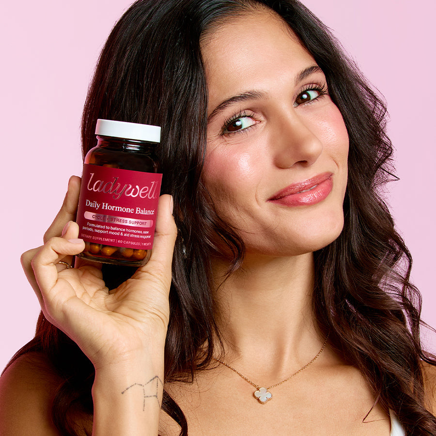 Woman holding a bottle of 'Lainiel' supplements against a pink background