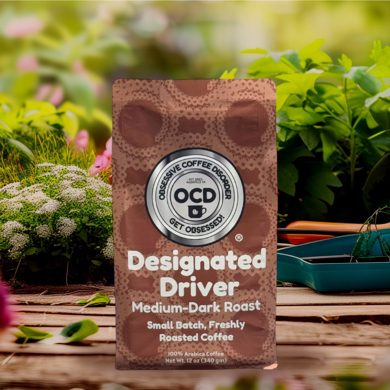 Coffee package labeled 'Designated Driver' by OCD Coffee on a wooden surface with plants in the background