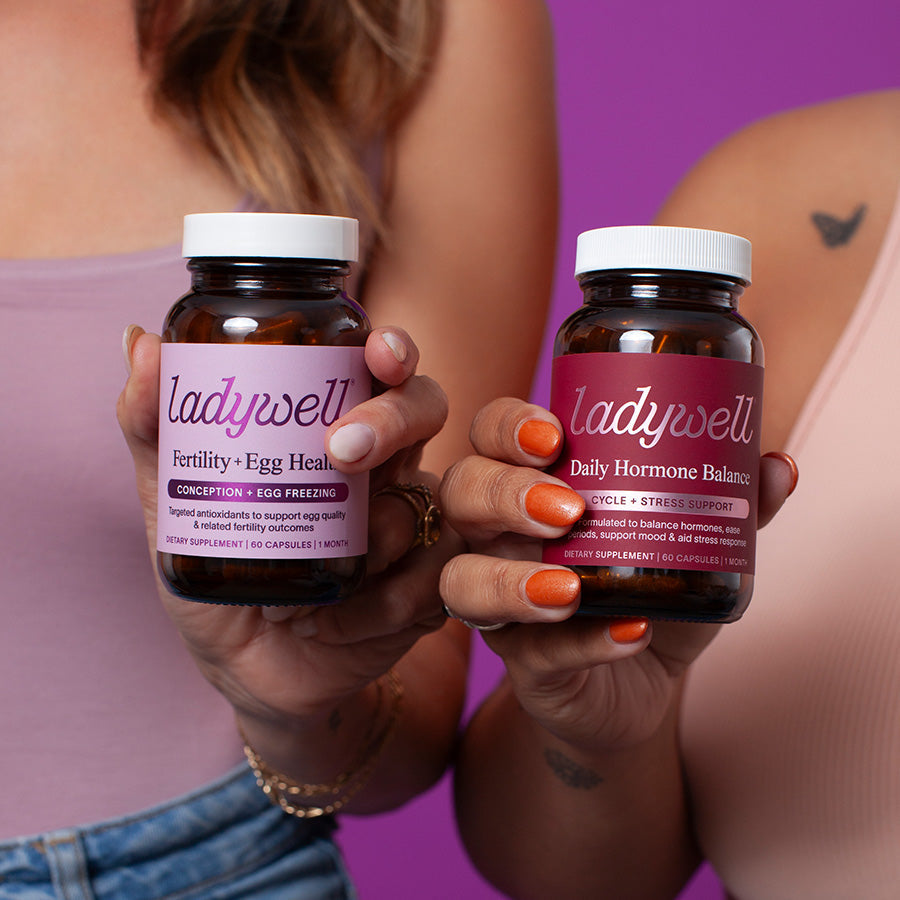 Two hands holding bottles of 'ladyswell' supplements against a purple background