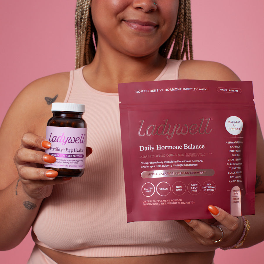 Woman holding Ladywell supplements against a pink background
