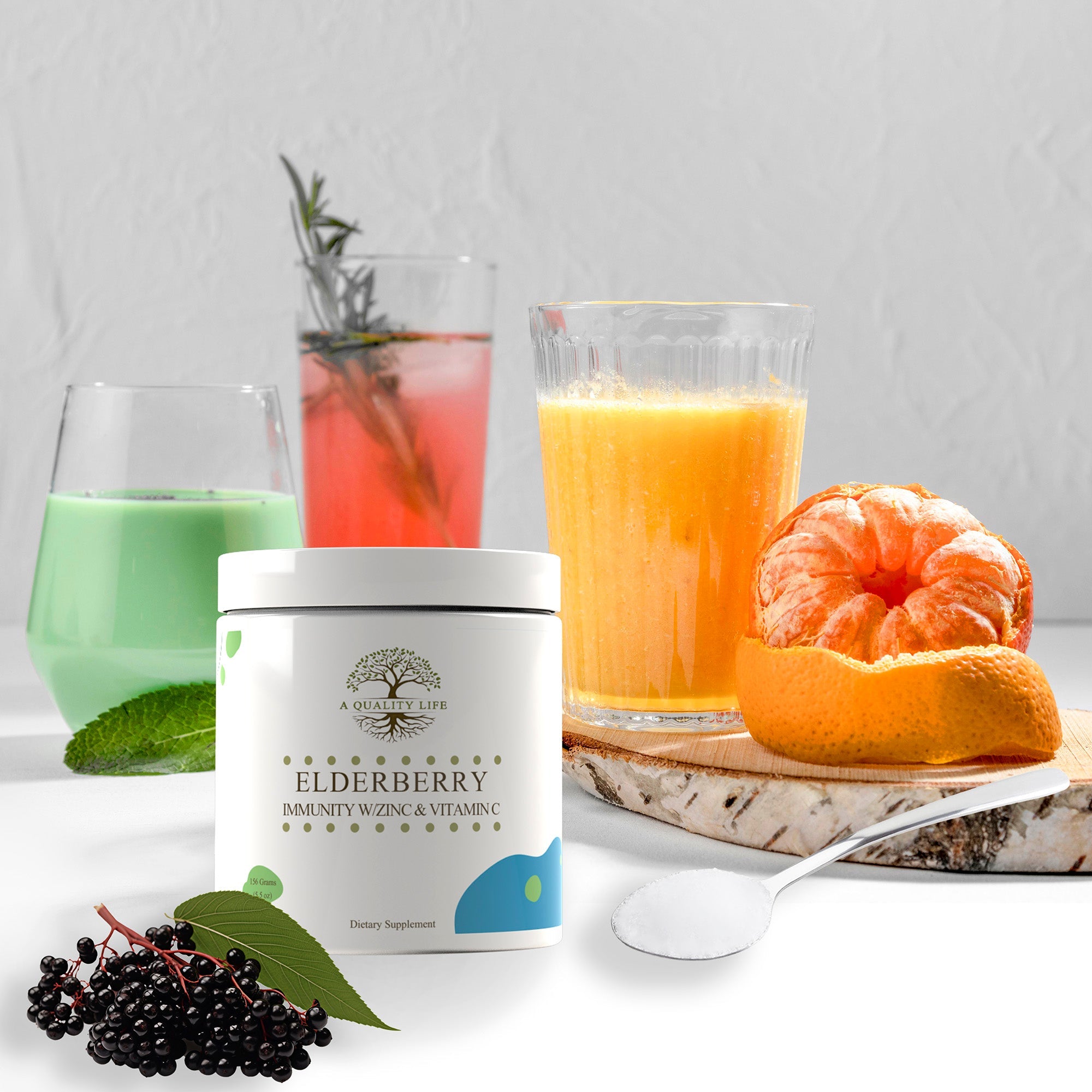 Elderberry supplement container with glasses of juice and a fruit on a white surface