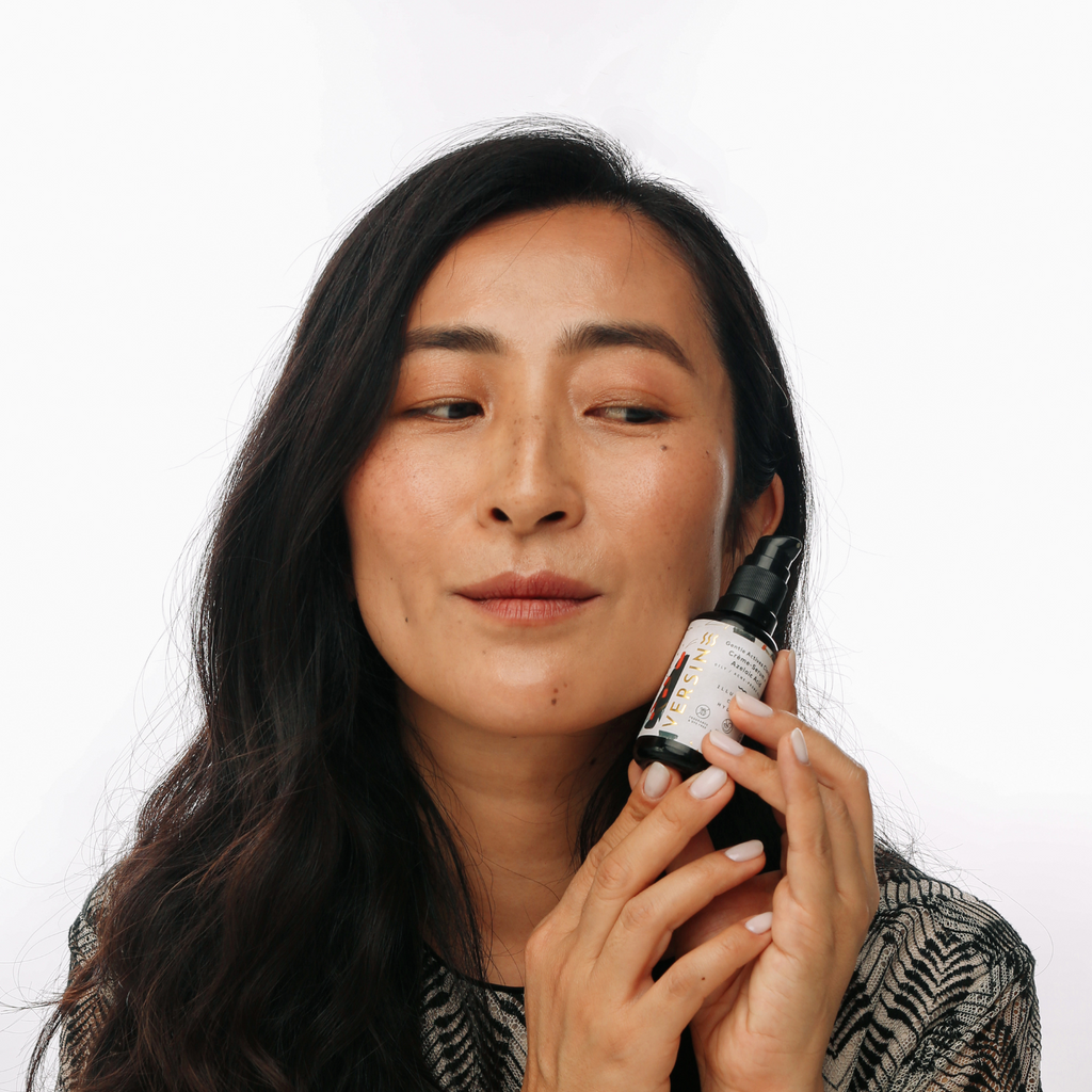Woman applying a skincare product to her face with a white background