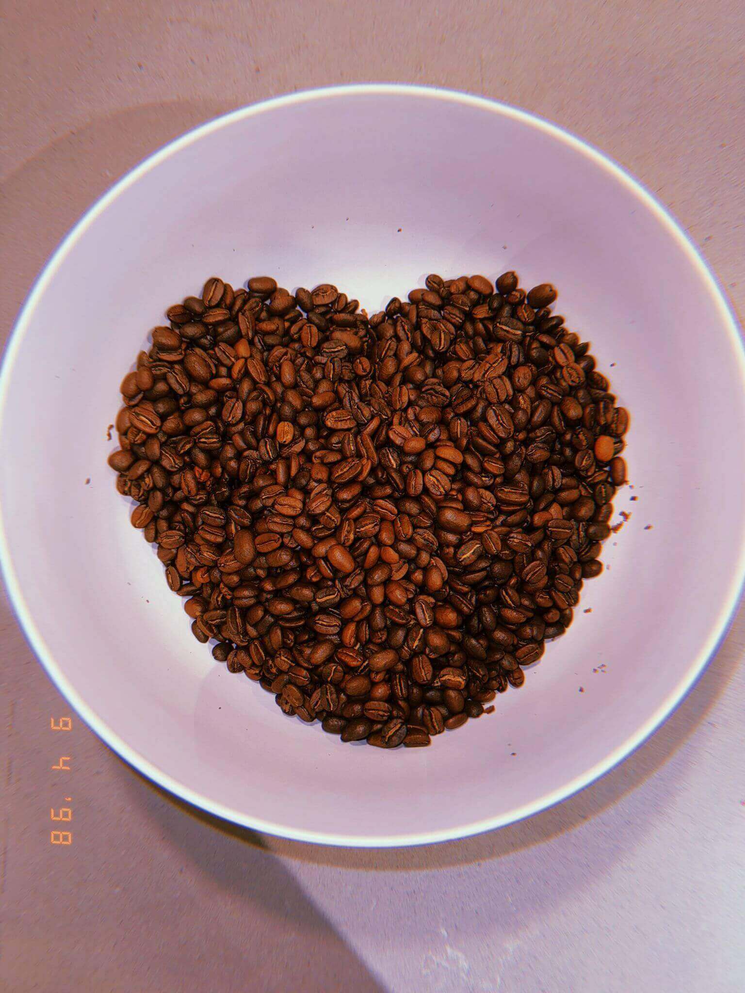 Heart-shaped pile of coffee beans on a white plate